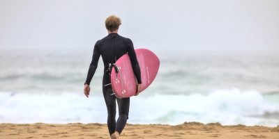 各类冲浪板排列在热带海滩沙滩上，包括长板短板泡沫板，色彩丰富