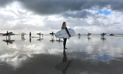 广东深圳大鹿湾海滩，冲浪者在翠绿海浪中练习，城市背景隐约可见